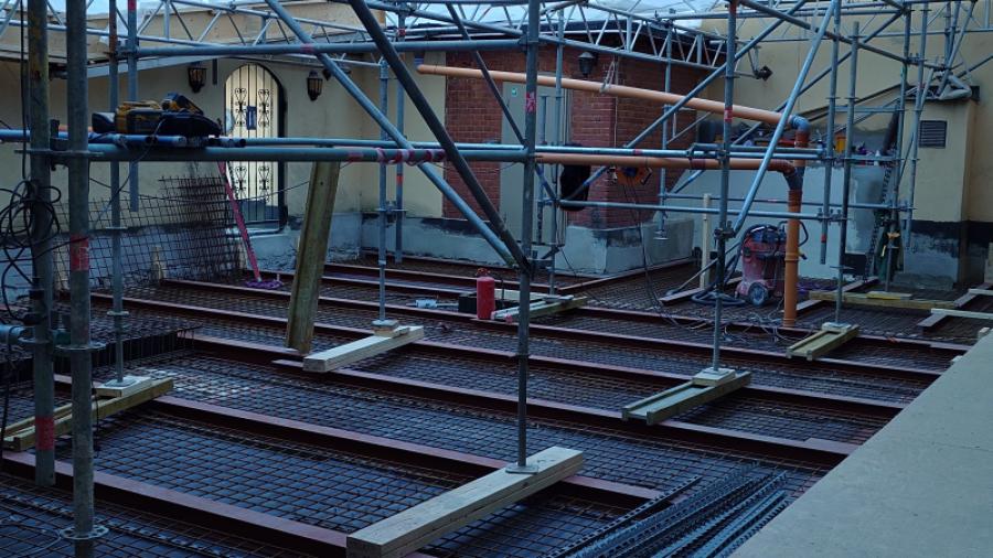 Gården den 30 mars 2025 under gårdsrenoveringen. Balkar med armeringsjärn.